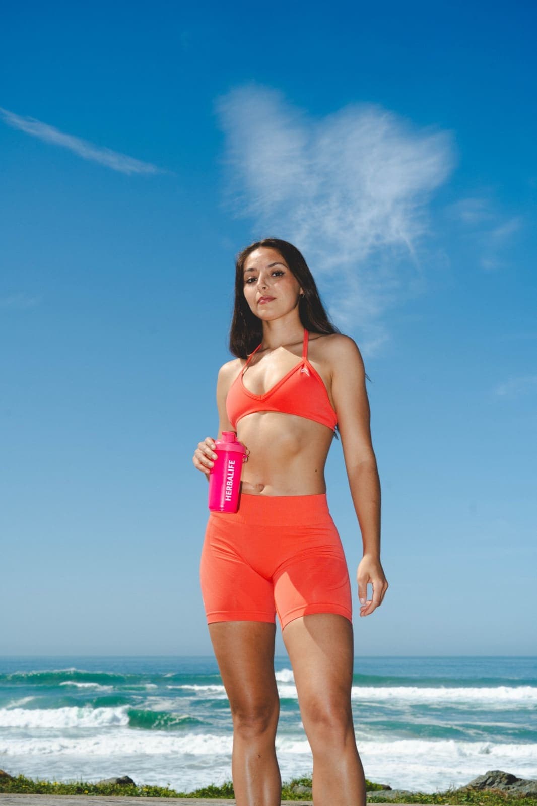 Summer Challenge 2026 · femme en tenue corail sur la plage